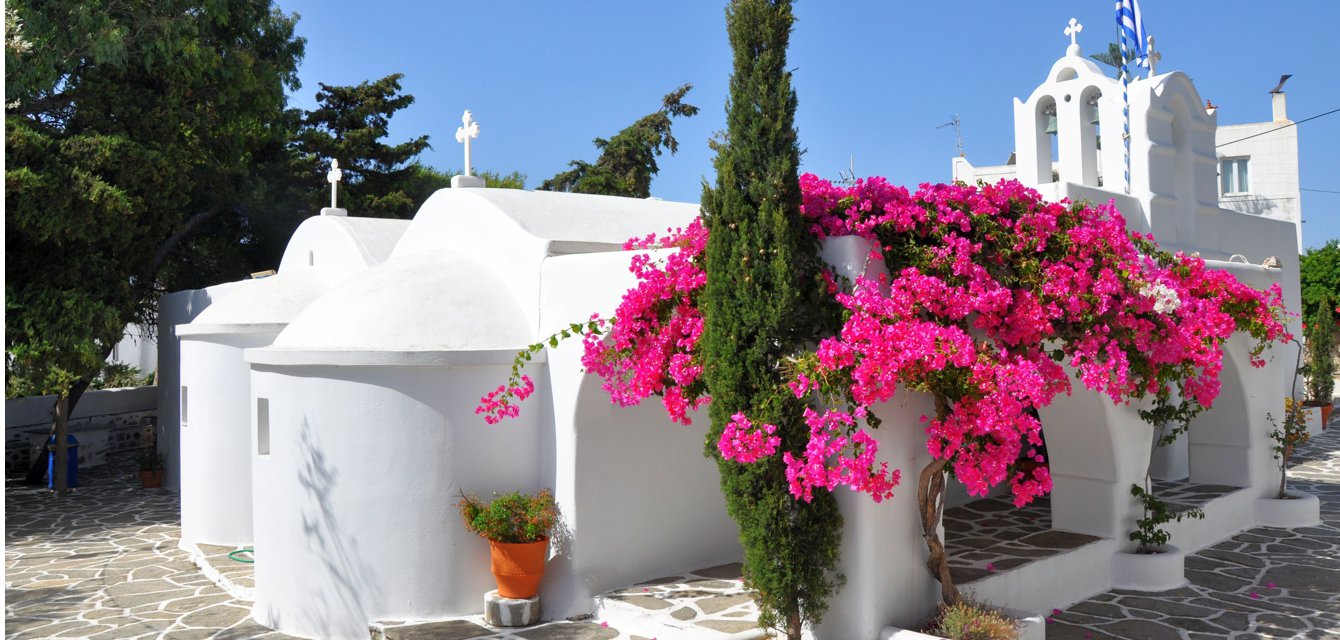 Picture-perfect traditional church in white, decorated with pink bougainvillea in Drios, Alonissos, Greece