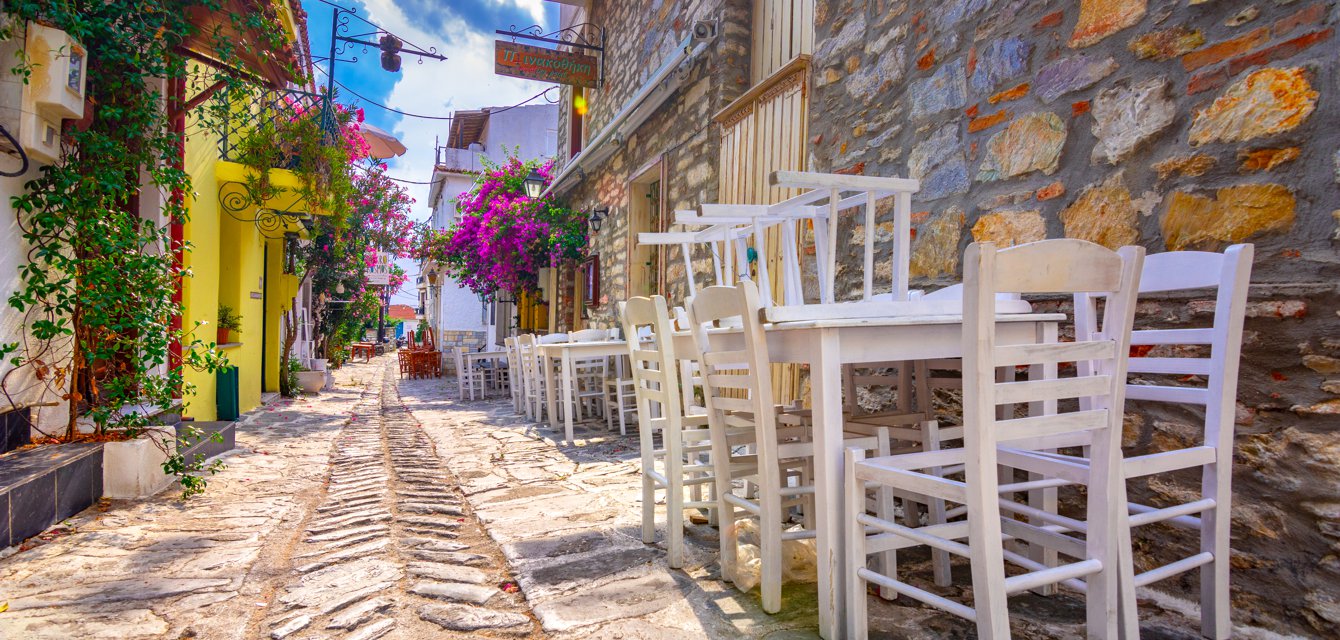 Colorful alley with quaint traditional taverns and bungavillae flowers in Skiathos, Greece
