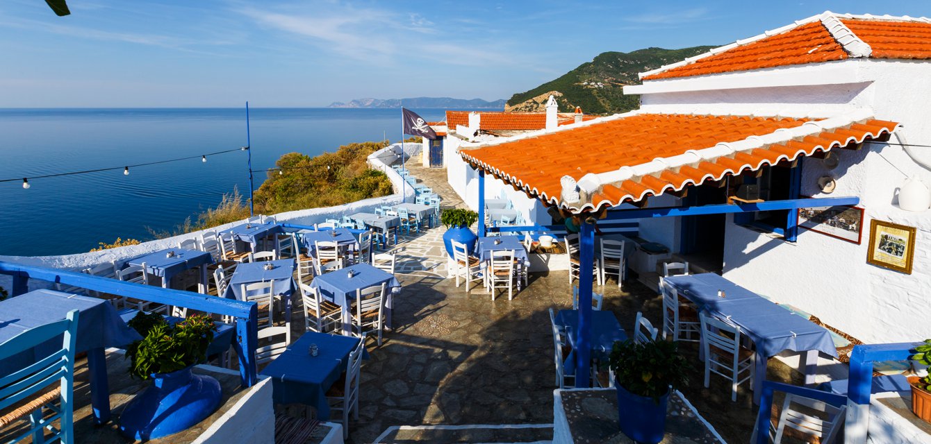 Traditional tavern with blue tables overlooking the Aegean in Skopelos, Greece